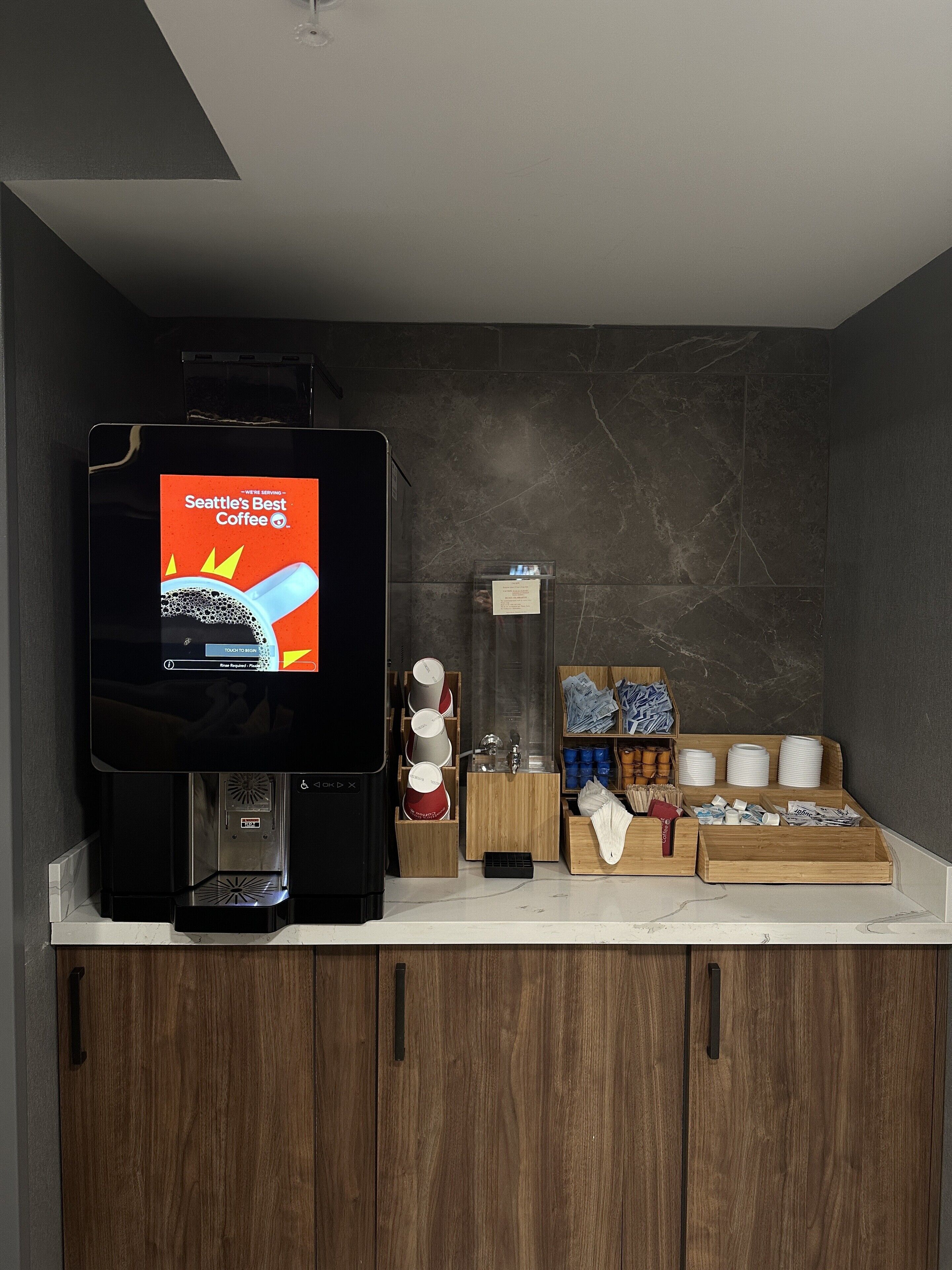A coffee station with a coffee machine, a menu display, and various coffee cups and mugs.
