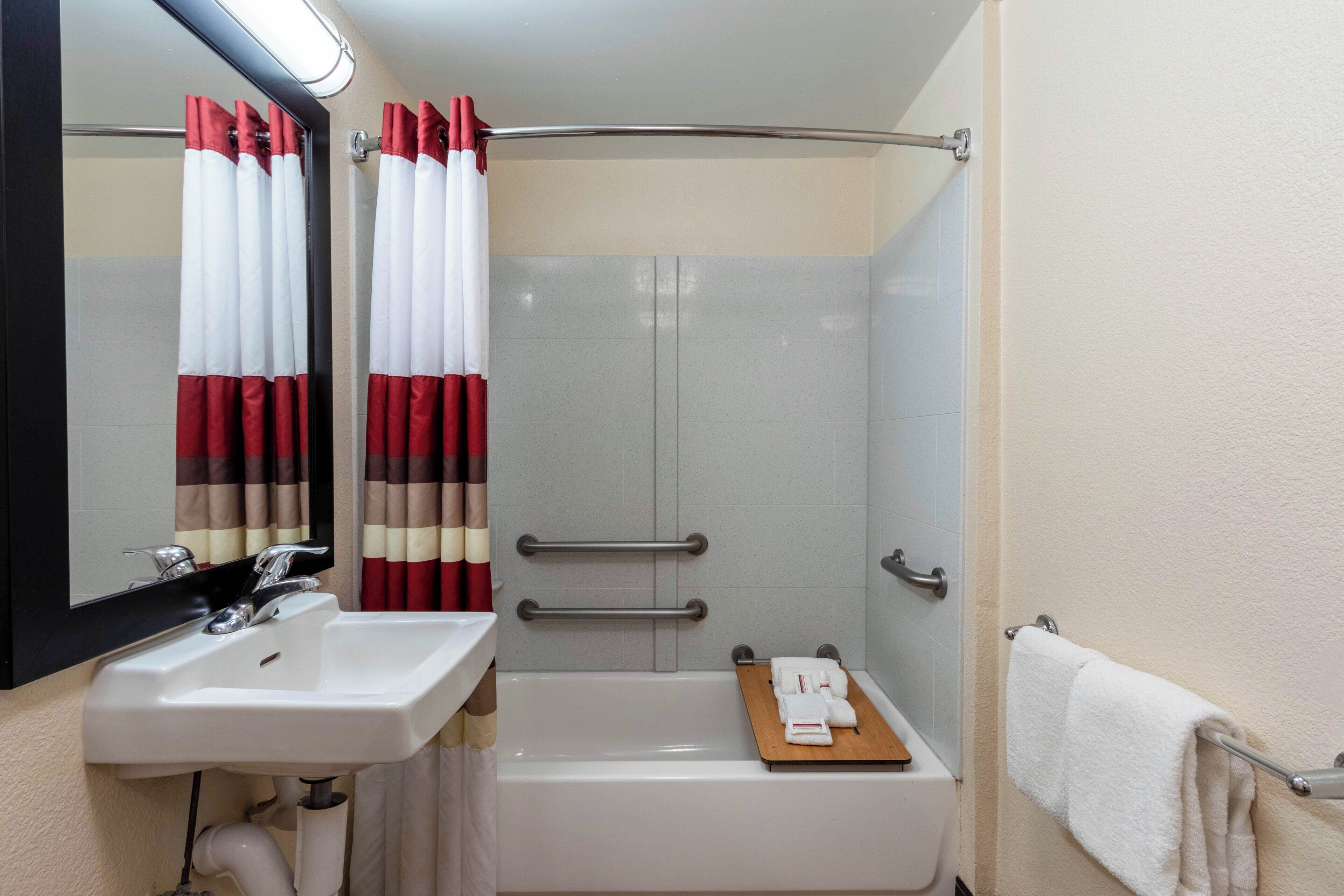 Une salle de bain équipée d’un lavabo, d’un miroir, d’une douche et d’un porte-serviettes.