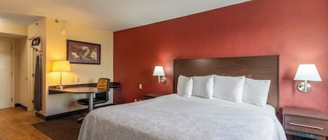 Una habitación de hotel con cama, escritorio, silla y dos lámparas de noche.