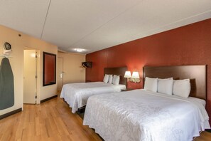 A hotel room with two beds, wooden flooring, a red accent wall, and a coat rack. - Red Roof Inn PLUS+ El Paso East (El Paso)
