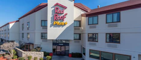 Un hôtel Red Roof Plus doté d’une façade moderne, de grandes fenêtres et d’une enseigne bien visible.