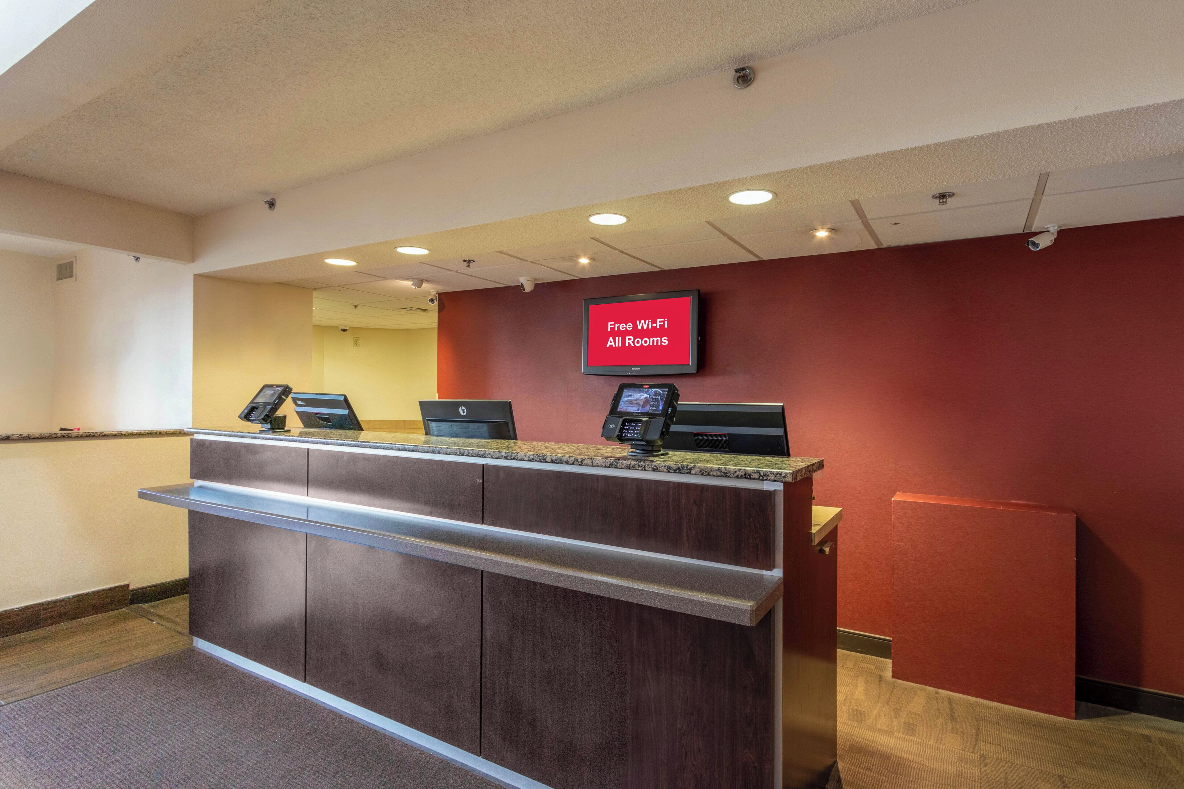 A hotel reception desk with a digital screen displaying 'Free Wi-Fi All Rooms'.