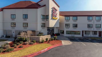 A multi-story hotel with a flat roof and a sign that reads 'Red Roof Plus.'