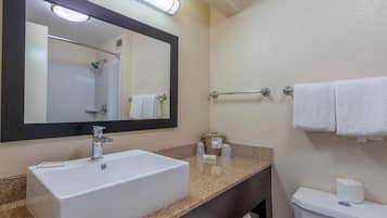 Een badkamer met een grote spiegel, een wit wastafelmeubel, een toilet en een handdoekhouder.