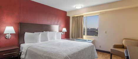 A hotel room with a large bed, two bedside lamps, a window with curtains, a chair, and a ceiling light.