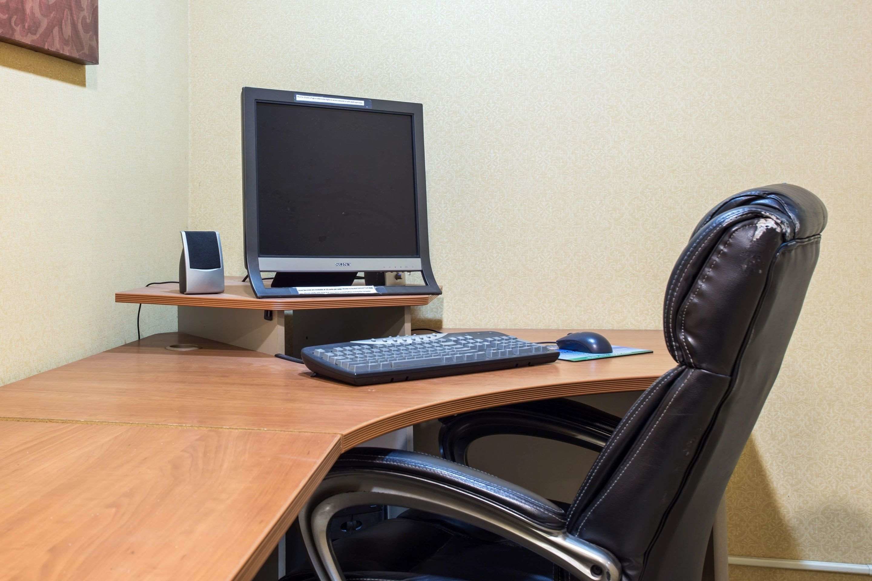A wooden desk with a computer monitor, keyboard, and mouse.