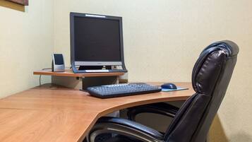 A wooden desk with a computer monitor, keyboard, and mouse.