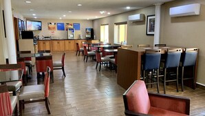 Ein großzügiges Restaurant mit mehreren Essbereichen, einer Küche im Hintergrund und einem an der Wand befestigten Flachbildfernseher.