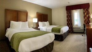 Ein Hotelzimmer mit zwei Betten, einem Schreibtisch, einer Lampe und einem Fenster mit Vorhängen.