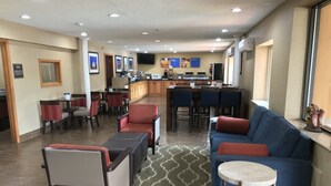 Eine Hotellobby mit Sitzbereichen, einer Bar und einer Küche im Hintergrund.