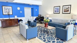 Una sala de estar moderna con sofás azules, una alfombra estampada y un mueble de madera.
