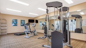 Un gimnasio con cintas de correr, elípticas y equipo de levantamiento de pesas.