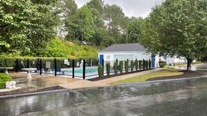 Propiedad residencial con piscina, jardín vallado y un pequeño edificio con puerta azul.