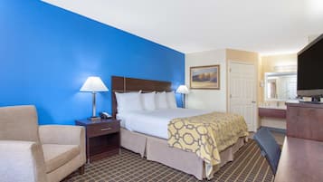 Une chambre d’hôtel comprenant un lit, des tables de chevet, une chaise, un bureau et un téléviseur.