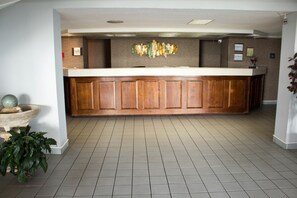 A reception area with a wooden reception desk, a stone planter, and a potted plant.