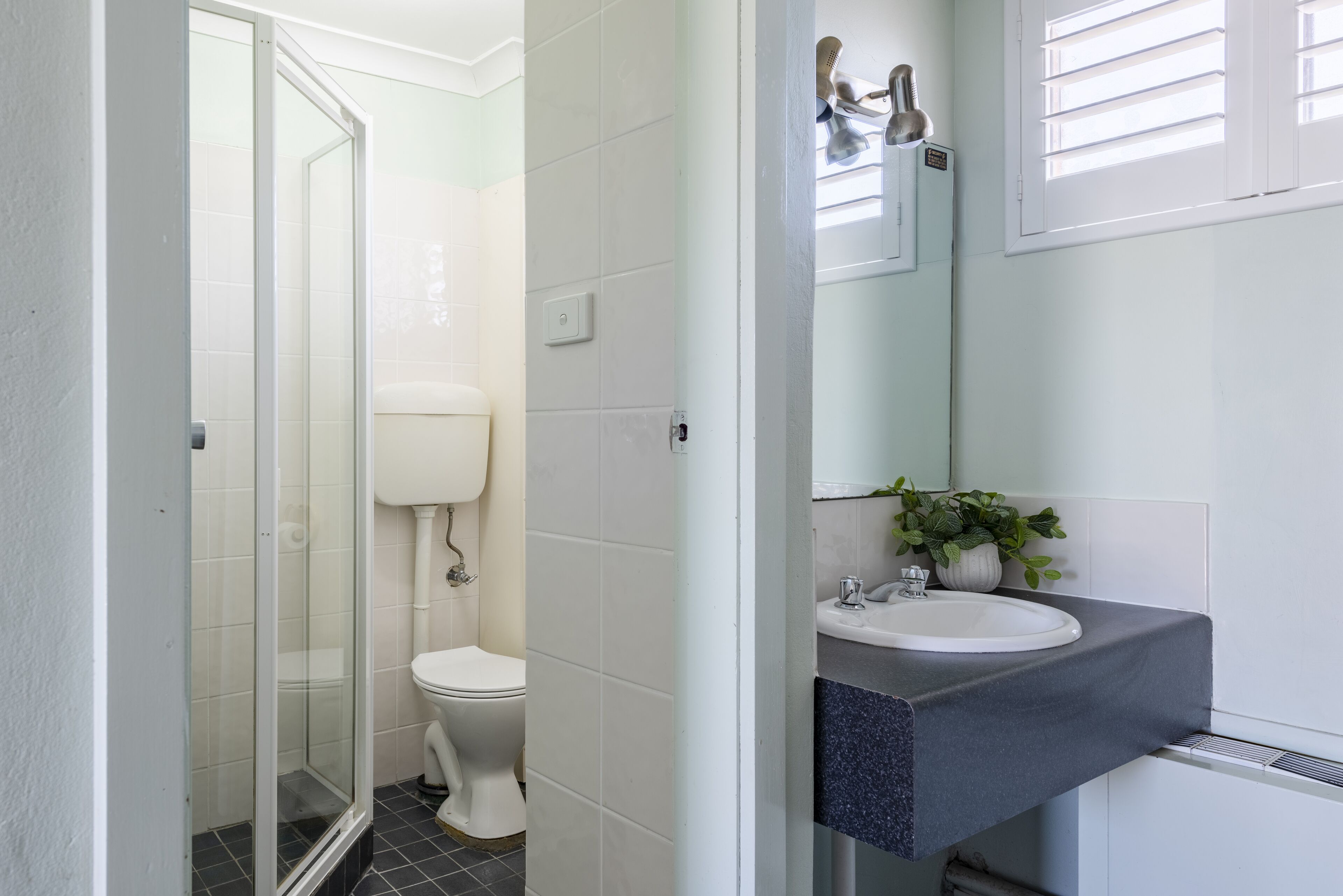 A bathroom with a glass shower enclosure, a toilet, and a sink with a mirror above it.