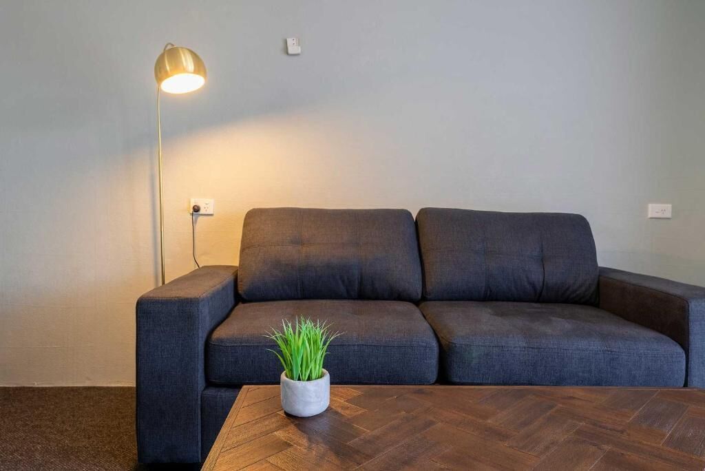 A modern living room with a dark grey sofa, a wooden coffee table, and a floor lamp.
