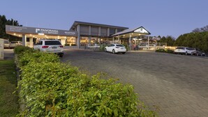 Ein modernes Hotel mit Empfangsbereich, Bistro und Bar. Vor dem Gebäude sind mehrere Autos geparkt.