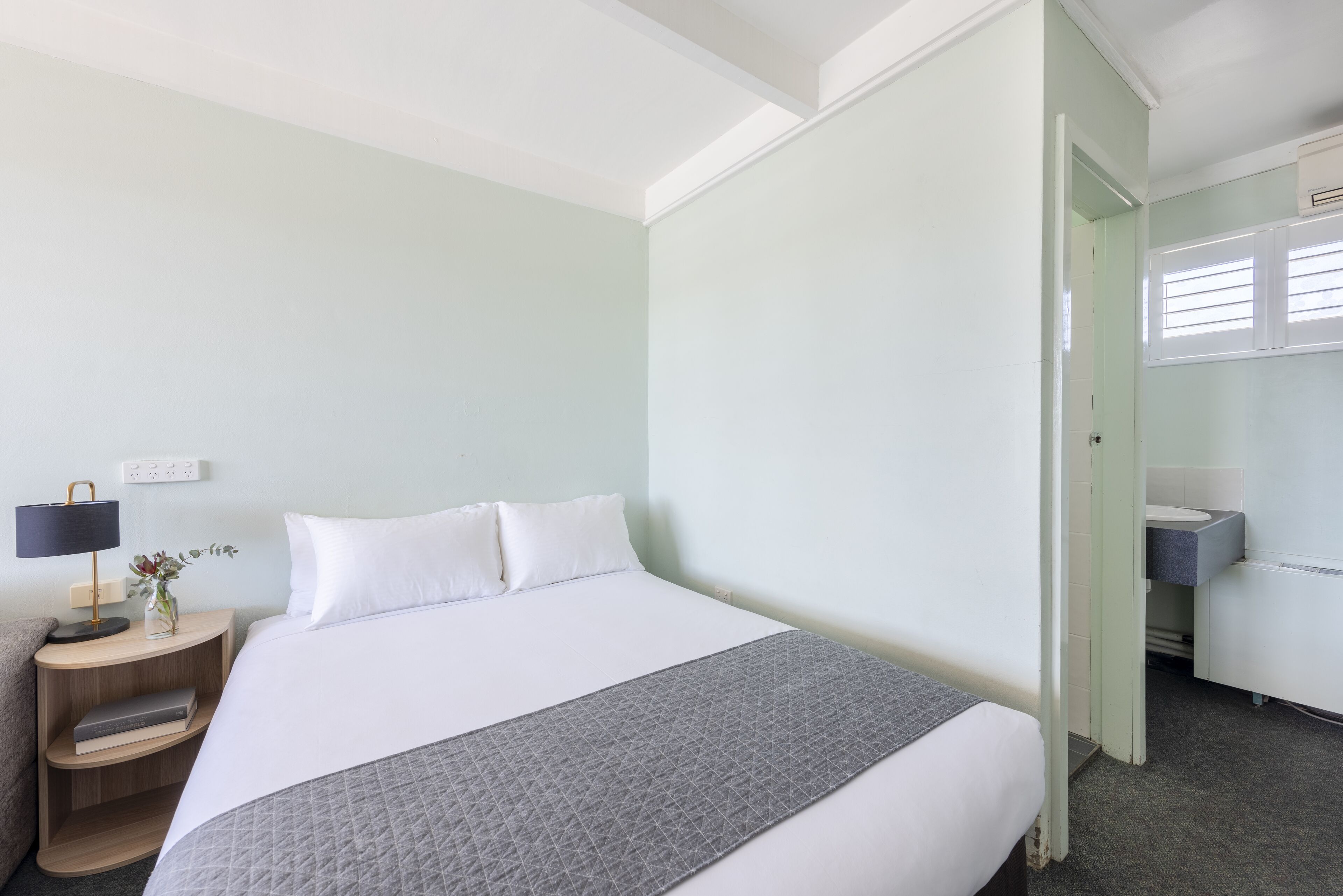 Une chambre d’hôtel avec un lit, une table de chevet, une lampe et une vue sur la salle de bain.