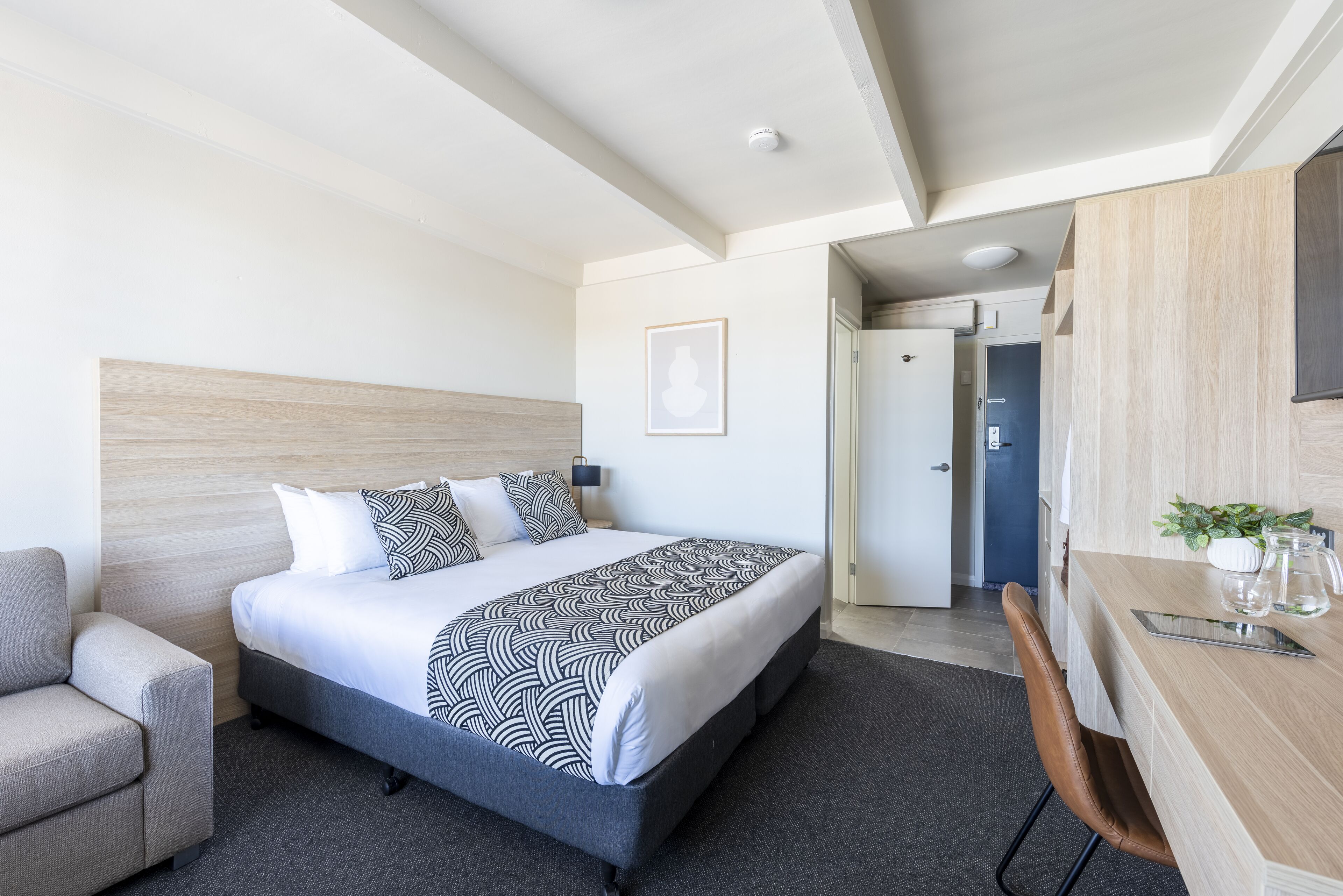A modern hotel room with a bed, a desk, and a chair.