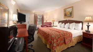 A hotel room with a bed, desk, chair, television, and lamps.