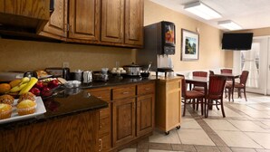 A kitchen with wooden cabinets, a black refrigerator, and a dining area with chairs and a table.