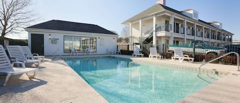 Una piscina al aire libre, sillones reclinables de piscina