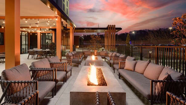 An outdoor seating area with sofas and chairs arranged around a central fire feature. - Hilton Garden Inn Knoxville Papermill Drive (Knoxville)