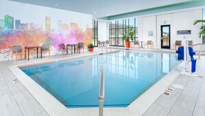 An indoor swimming pool with a cityscape mural, seating area, and clear signage. - Hilton Garden Inn Knoxville Papermill Drive (Knoxville)