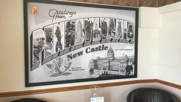Un cartel de bienvenida enmarcado para New Castle, con fotografías históricas y el edificio de la capital del estado.