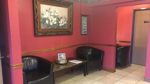 A reception area with two black leather chairs, a small table with a framed picture, and a door labeled "OFFICE".
