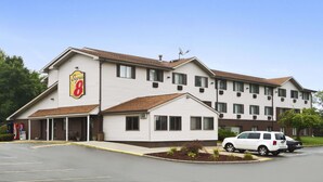 A Super 8 motel with a two-story structure, a covered front porch, and a parking lot with two cars.