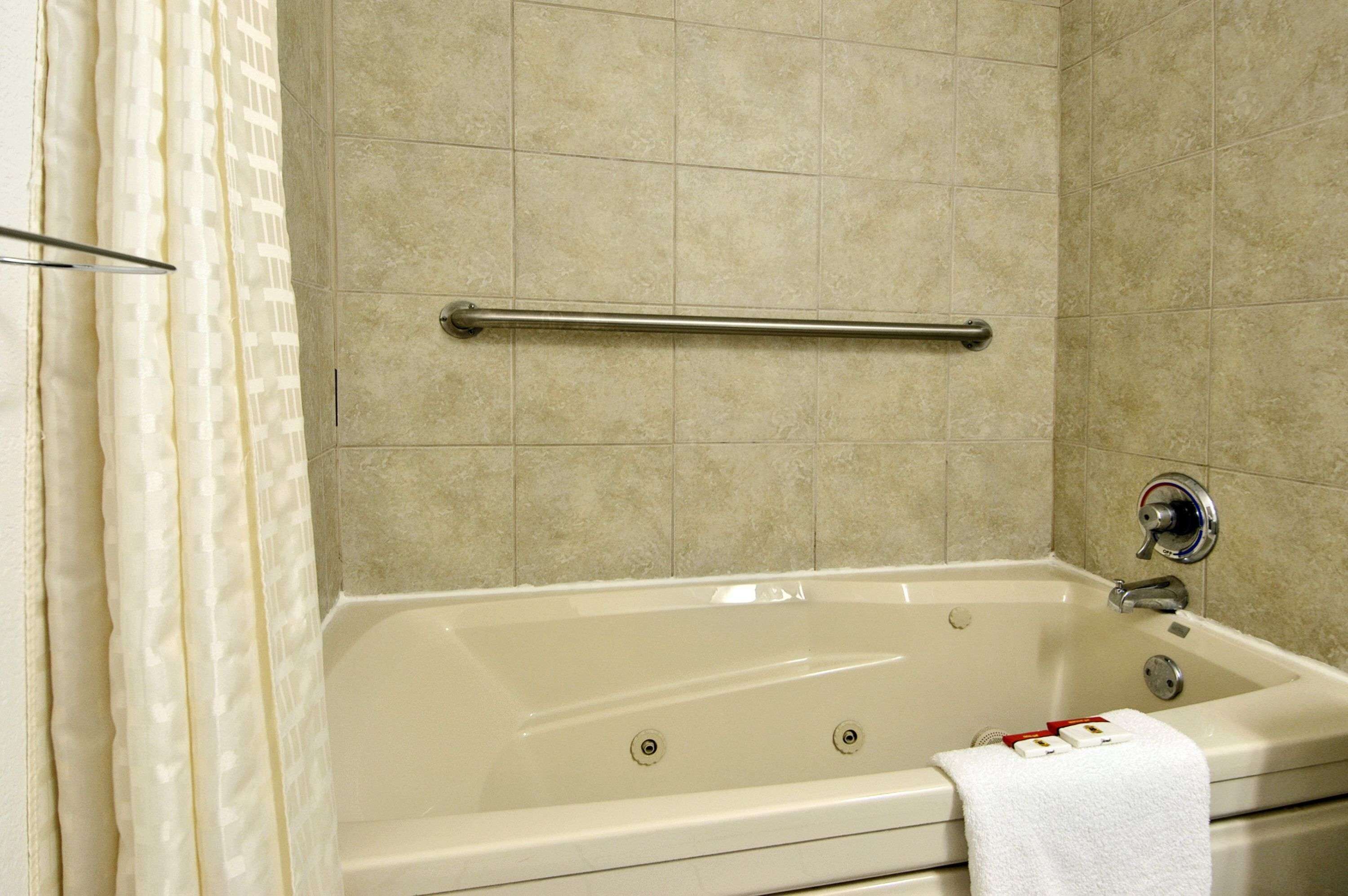 A bathroom with a bathtub, a towel rack, and tiled walls.