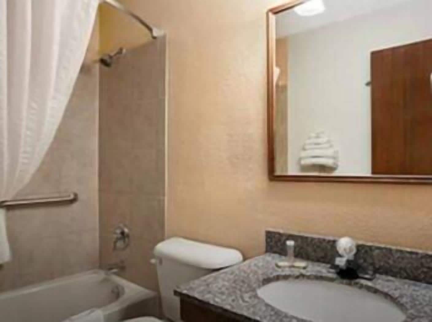A bathroom with a bathtub, toilet, sink, and a mirror.