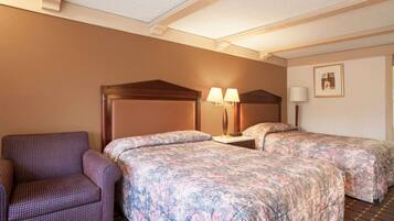 A hotel room with two beds, a chair, and a nightstand with lamps.