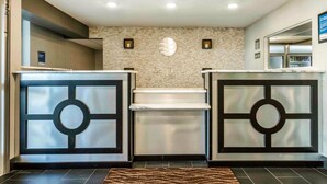 A reception area with a stone wall, a central fireplace, and two reception desks with circular designs. - Comfort Inn Memphis Airport West (Memphis)