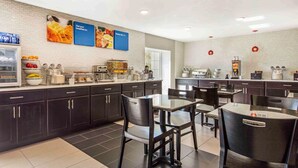 A modern kitchen area with dark cabinets, a coffee machine, and a breakfast bar. - Comfort Inn Memphis Airport West (Memphis)