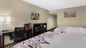 Una habitación de hotel con escritorio, silla, televisión y dos camas.