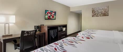 Una habitación de hotel con escritorio, silla, televisión y dos camas.