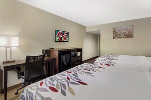 Una habitación de hotel con escritorio, silla, televisión y dos camas.