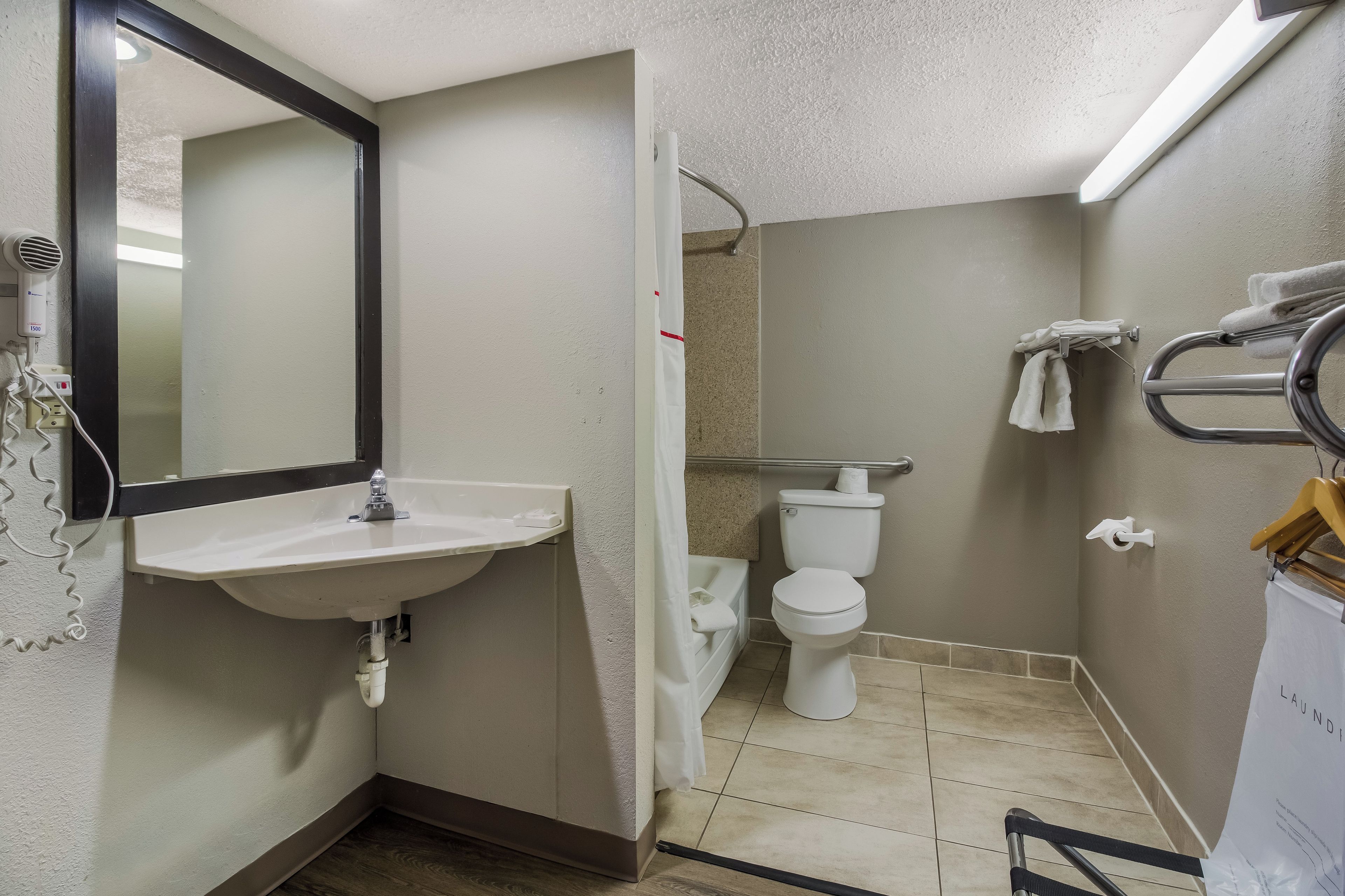 Ein Badezimmer mit Waschbecken, Spiegel, Toilette und Duschbereich.