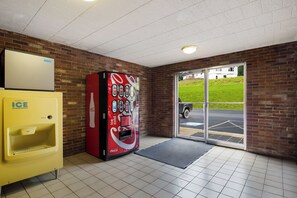 Un distributeur automatique orné du logo Coca-Cola, doté d’un distributeur de glaçons jaune et d’une porte en verre donnant sur l’extérieur.