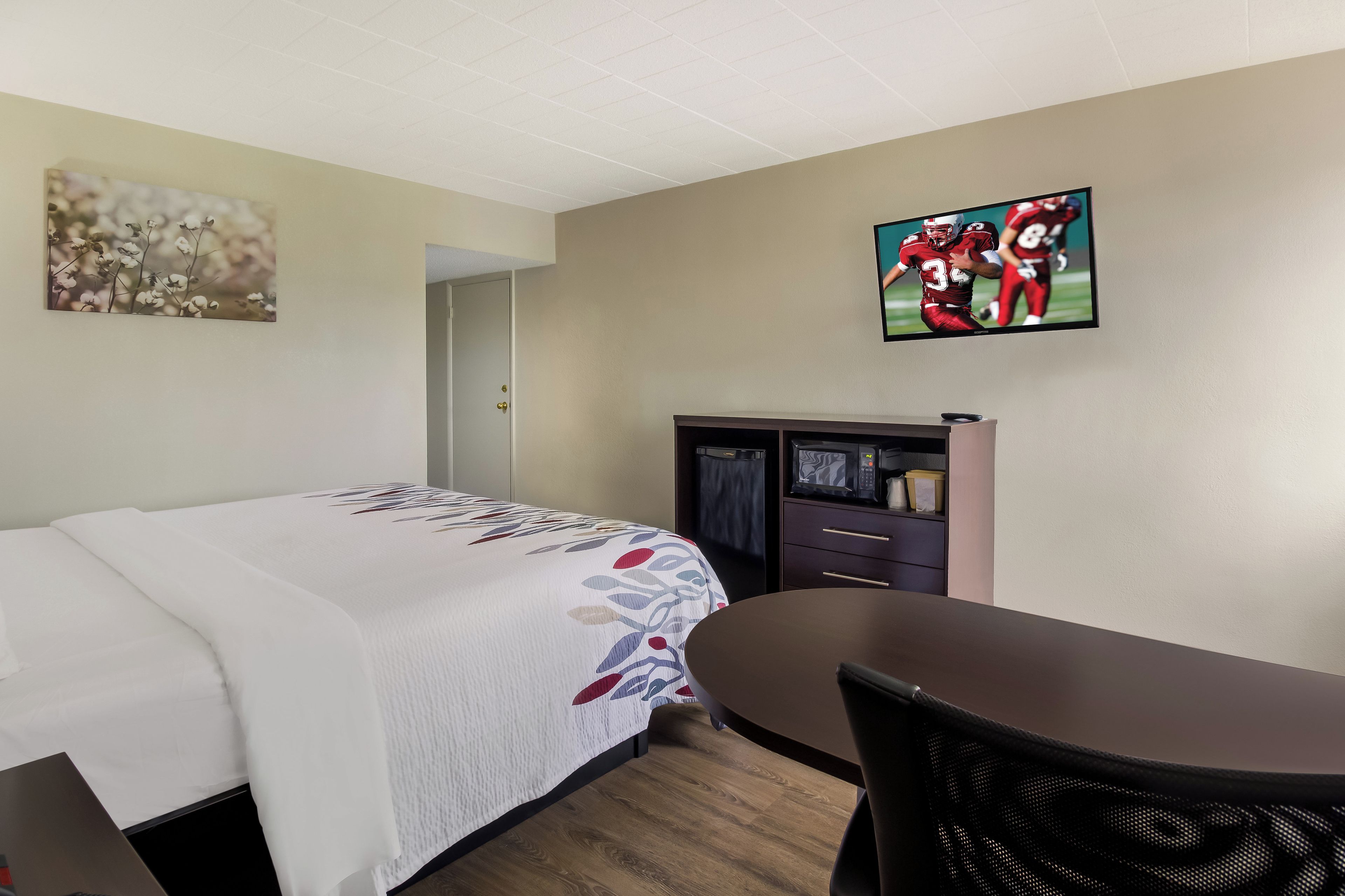 Una habitación de hotel con cama, escritorio, televisor y puerta.