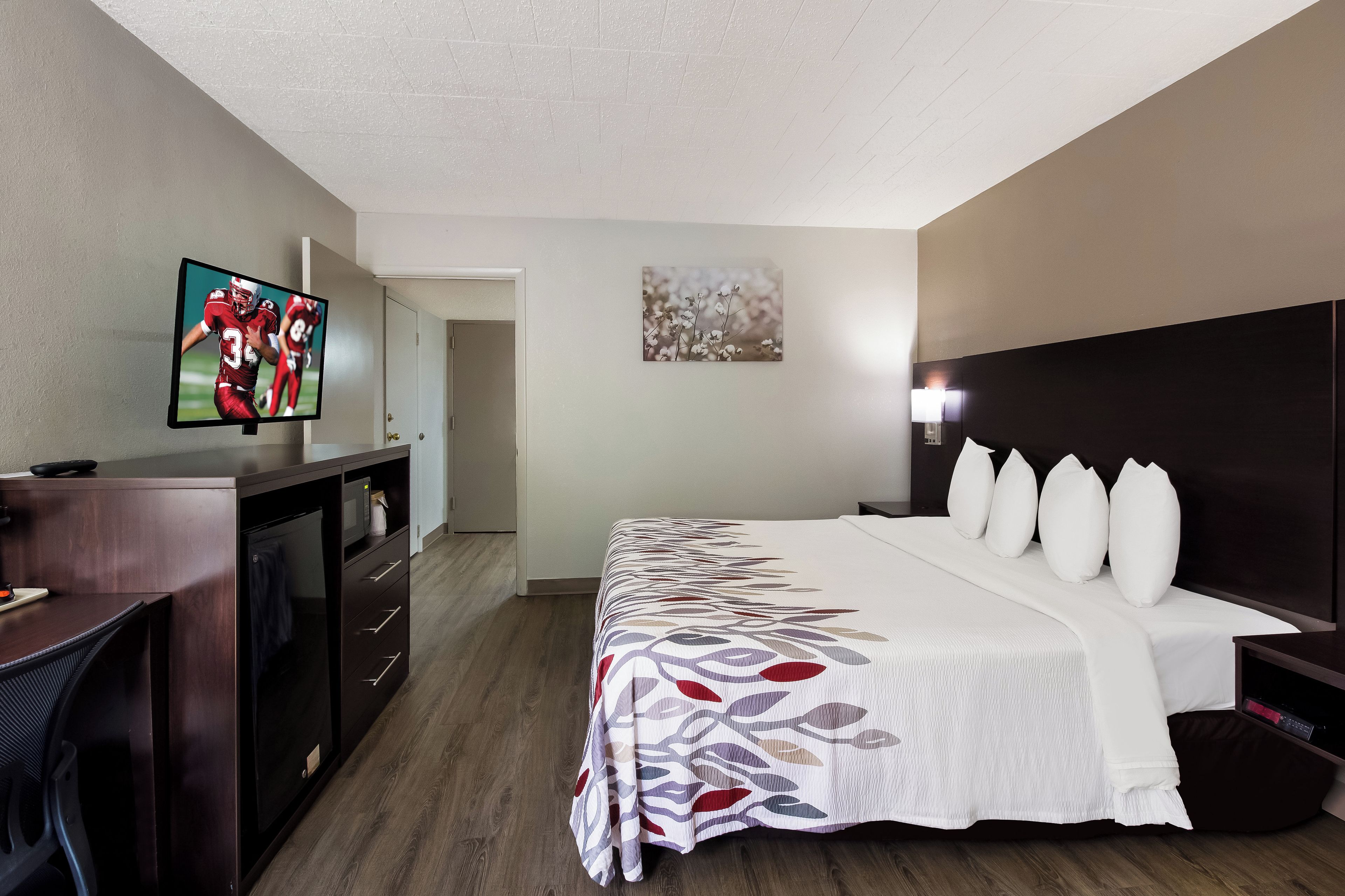 Une chambre d’hôtel avec un lit, un bureau, une télévision et une porte.