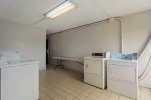A laundry room with a washing machine, dryer, and a table with a Whirlpool appliance.