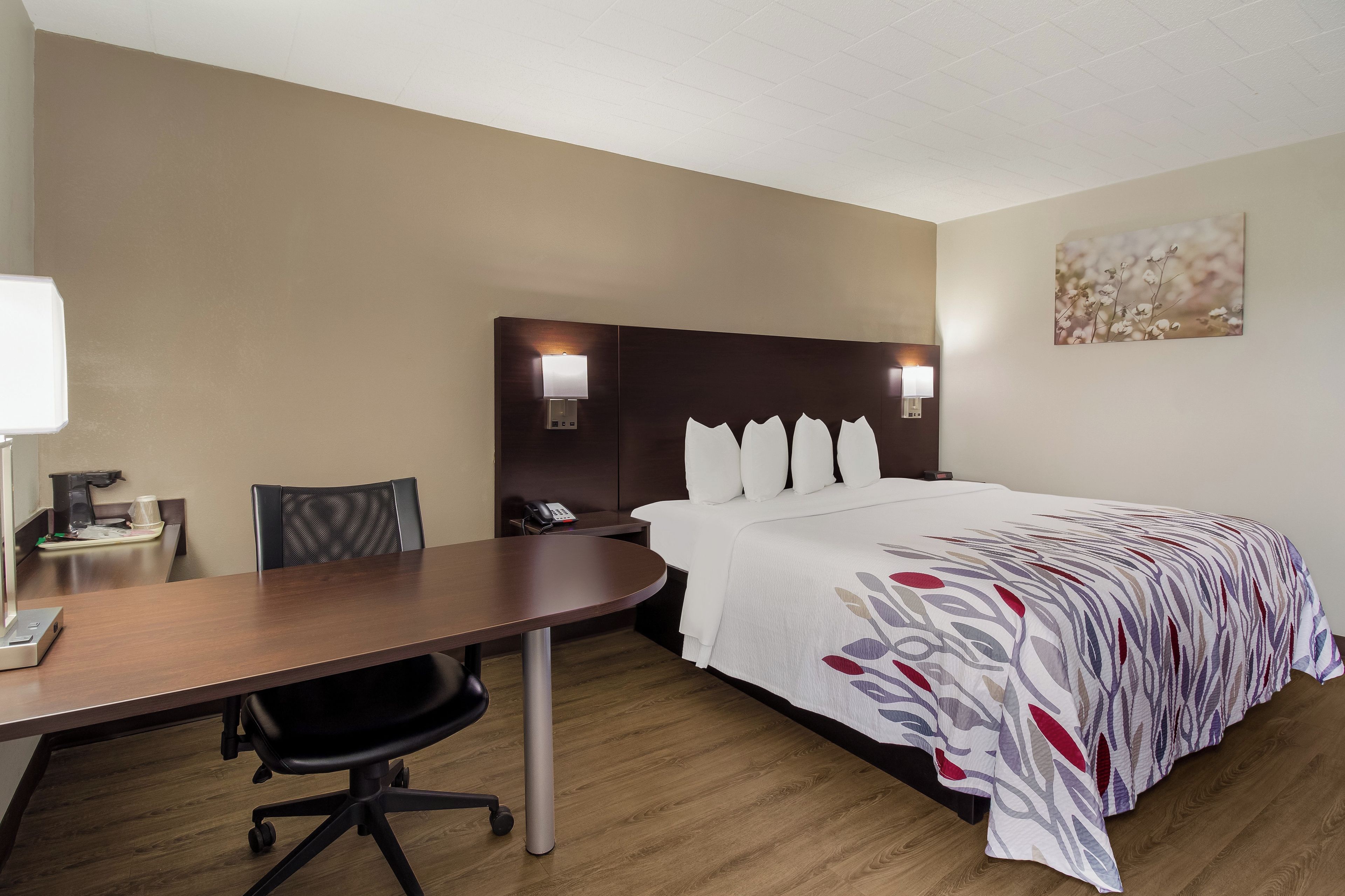 Habitación de hotel con cama, escritorio y silla. Hay dos lámparas de pared a cada lado de la cama.