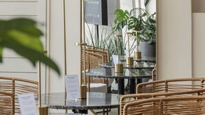 A restaurant interior with wicker chairs, a glass table, and a large mirror reflecting the room. - Feir's Park Hotel (Buenos Aires)