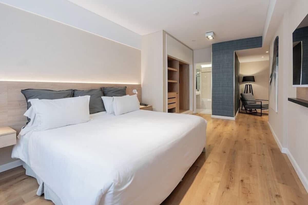 A modern bedroom with a large bed, built-in wardrobe, and a walk-in closet.