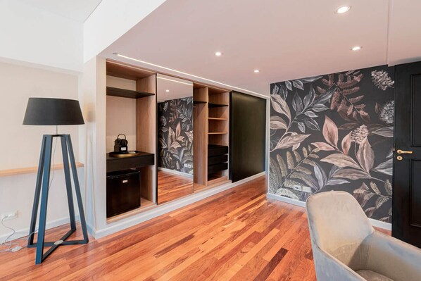 A modern room with a wooden floor, a desk with a lamp, a chair, and a wardrobe with mirrored doors. - Feir's Park Hotel (Buenos Aires)