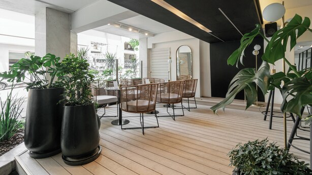 A modern indoor space with a wooden floor, black and white furniture, and large potted plants. - Feir's Park Hotel (Buenos Aires)